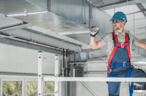 HVAC Professional Worker Checking Last Points of the System From Aluminium Scaffolding. Heating and Cooling Industry Theme.