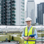 An engineer's portrait is examining the cooling tower air conditioner of a huge industrial building to control airflow.