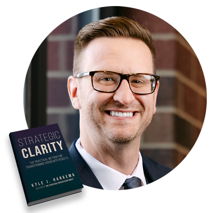 circle_kyle2 Smiling man in suit and glasses beside a book titled 'Strategic Clarity'.